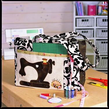 Schwarz-weiß gemusterte Utensilo-Tasche mit applizierter Nähmaschine, Schneidematte, Maßband und Garnrollen