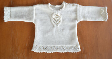 Hellfarbener gestrickter Kinderpullover mit Ajourborte am Saum und an den Ärmeln