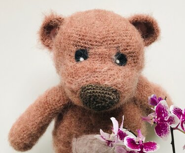 Nahaufnahme eines gehäkelten Amigurumi Teddybären, Fokus auf Nase, Augen und die flauschige Maschenstruktur