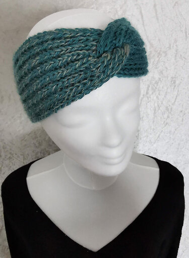 Teal marled knitted headband with center twist on white mannequin bust
