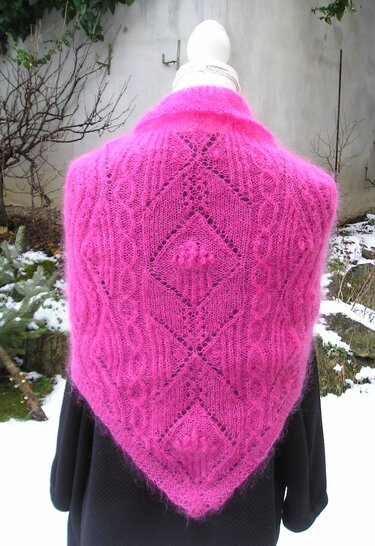 Fuchsiafarbenes gestricktes Dreieckstuch mit Ajour- und Zopfmustern, Rückansicht auf Schaufensterpuppe vor winterlicher Kulisse