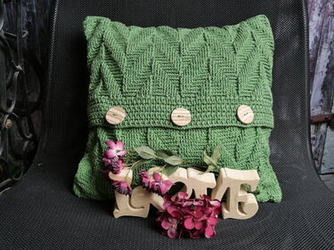 Grüner gehäkelter Kissenbezug mit Zickzackmuster und drei Holzknöpfen