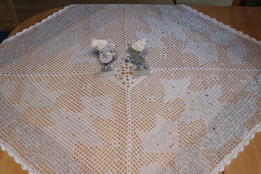 Quadratisches, helles Häkeldeckchen mit Lochmuster auf Holztisch