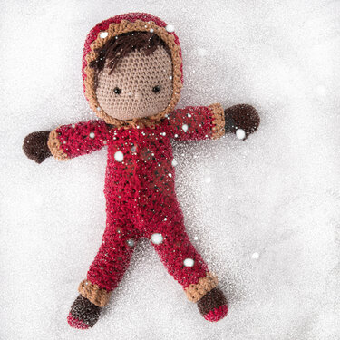 Rote Amigurumi-Puppe mit Kapuze im Schnee