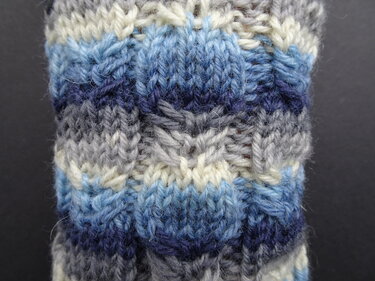 Nahaufnahme gestrickte Socke in blau, grau und weiß mit Streifen- und Strukturmuster