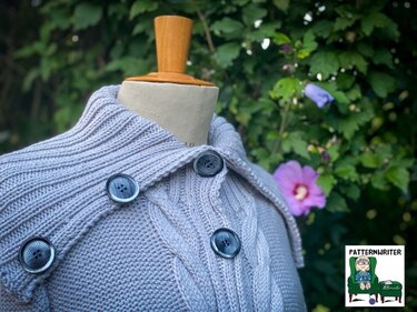 Hellgrauer Strickcardigan mit Zopfmuster, geripptem Schalkragen und dunklen Knöpfen auf einer Schneiderpuppe vor grünem Hintergrund mit lila Blüten.