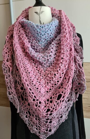 Gehäkeltes Dreieckstuch mit Farbverlauf in Blau, Rosa und Lila, drapiert an einer Schaufensterpuppe