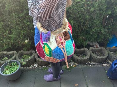 Bunte gehäkelte Umhängetasche im Patchwork-Stil mit Kordelzug an der Schulter getragen