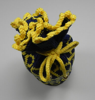 Gestrickter Dekobeutel mit gelber Rüsche, Kordelzug und Ösen, von oben gesehen