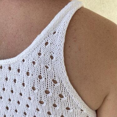 Nahaufnahme eines weißen Stricktops mit Lochmuster an der Schulter