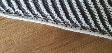 Close-up of a grey and white two-tone crochet showing stitch detail and a neat white edge.