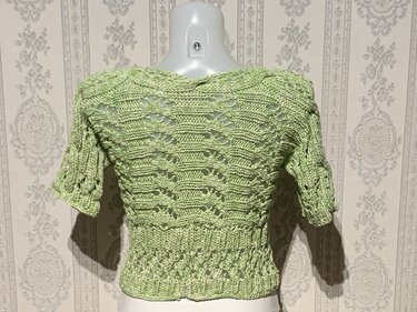 Rückenansicht eines hellgrünen, gestrickten Damenpullovers mit Ajour- und Rippmuster auf Torso-Mannequin