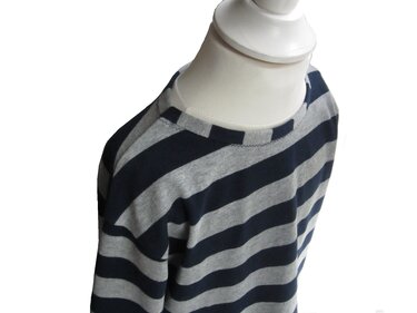 Detailaufnahme: Kinder‑Shirt mit Raglanärmeln, eingefasstem Rundhalsausschnitt und sichtbarem Zierstich, blau‑graue Streifen