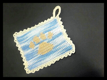 Quadratischer gehäkelter Topflappen hellblau-weiß mit hellbeiger Pfote und Aufhängeschlaufe