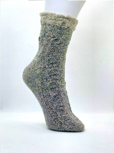 Handgestrickte Socke in melierten Erdtönen mit Zopf- und Rippenmuster und gewelltem Bündchen auf einem Fußmodell.