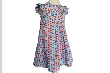 Hellblaues Babykleid mit rotem Erdbeer- und Kirschmuster und Rüschenärmeln.