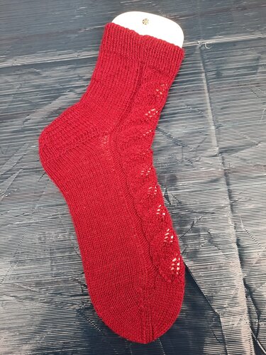 Rote gestrickte Damensocke mit Lochmuster auf dunklem Untergrund