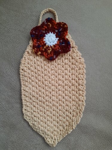 Beiger gehäkelter Topflappen mit braun-orange-weiß-blauer Blumenapplikation und Aufhängeöse