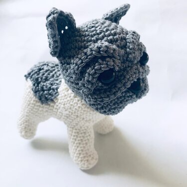 Gray and white crocheted amigurumi dog with large black eyes