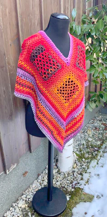 Gehäkelter V-förmiger Poncho mit Diamantlochmuster und farbigen Streifen auf Mannequin