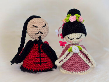 Handgehäkelte Eierwärmer-Puppen in Rot-Schwarz und Rosa-Beige mit gestickten Gesichtern