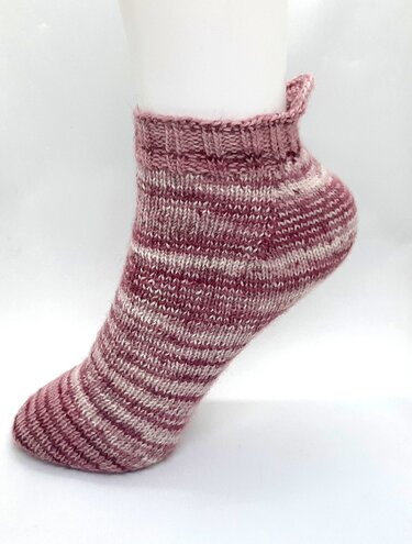 Gestrickte Kurzsocke in Beere und Creme mit Ringelmuster und kleiner Fersenlasche auf weißem Fußmodell.