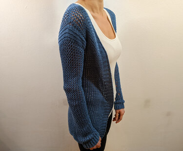 Dunkelblaue, offene Strickjacke mit Lochmuster über weißem Top.