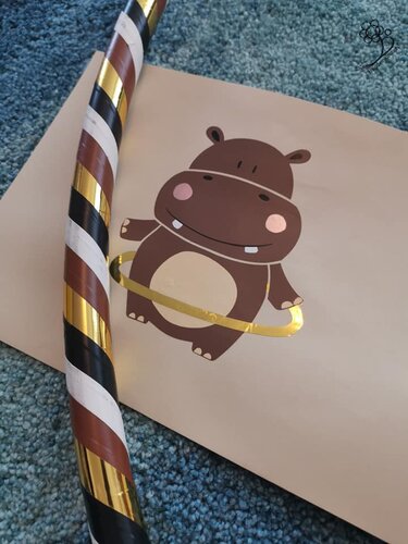 Cartoon-Nilpferd mit goldfarbenem Hula-Hoop auf beigem Papier, gestreifter Reifen auf blauem Teppich