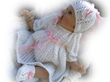 Weißes gestricktes Baby-Set mit Mütze, Kleid und Söckchen, rosafarbene Bänder