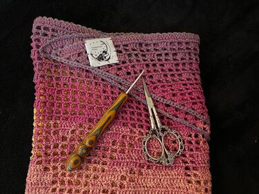 Gehäkeltes Tuch mit Farbverlauf und Lochmuster, Häkelnadel mit Holzgriff, verzierte Stickschere und angenähtes Label.