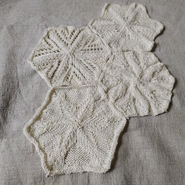 Gestrickte sechseckige Motive aus hellem Garn mit sternförmigem Muster auf Leinen