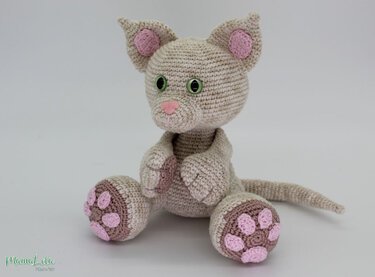 Gehäkelte Amigurumi‑Katze in Beige mit rosa Details und grünen Augen