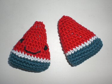 Zwei gehäkelte Mini-Wassermelonen, rot mit weißem Streifen und grünem Rand, eines mit aufgesticktem Gesicht