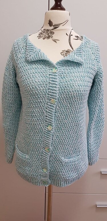 Gehäkelte hellblaue Damenjacke mit Umlegekragen, Knopfleiste und Taschen auf Schneiderpuppe