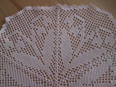 Gehäkeltes Deckchen in hellem Beige mit Gitter- und Rautenmuster auf Holzuntergrund