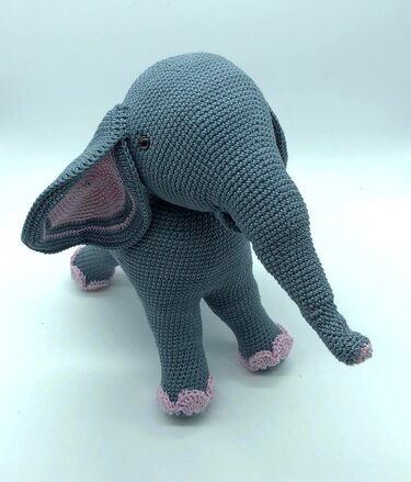 Gehäkelter grauer Amigurumi-Elefant mit rosa Innenohren und Zierkanten, stehende Ansicht