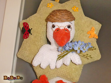 Gehäkelter Storch mit Brille und Blumen an sternförmigem Türkranz