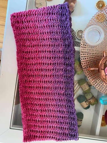 Gehäkelter Loop mit Pink‑Violettem Farbverlauf auf Tisch neben Wollknäueln
