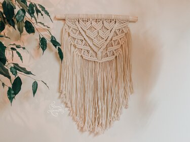 Neutral macramé wall hanging with geometric diamond knots and long fringe on a wooden dowel