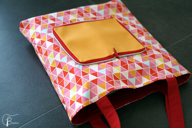 Bunte Stoff-Einkaufstasche mit geometrischem Muster, senffarbenem Reißverschlussfach und roten Tragegriffen