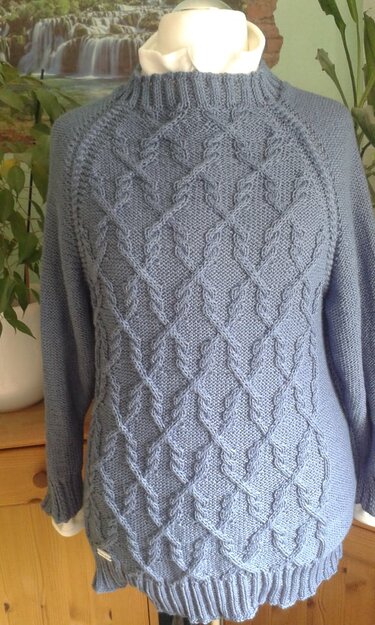 Hellblauer gestrickter Pullover mit geometrischem Zopfmuster und kleinem Stehkragen auf einer Büste präsentiert