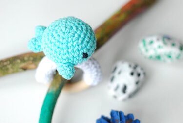 Türkiser gehäkelter Wal-Greifling an einem Holzast hängend