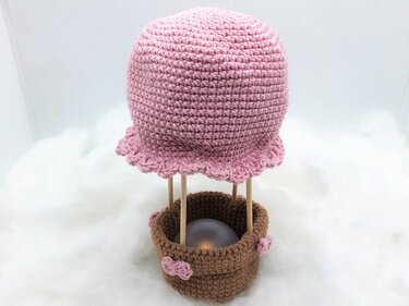 Gehäkelter rosa Heißluftballon Amigurumi mit braunem Korb und Holzstäbchen