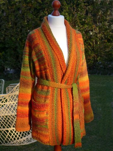 Gestrickte Damen-Wickeljacke in Orange- und Gr	nt	önen mit Bindeg	rtel und Taschen auf einer Schneiderpuppe.