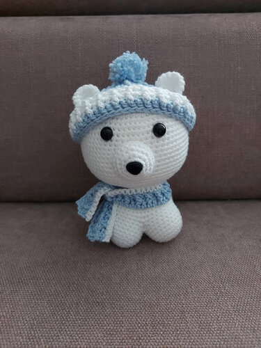 Weißer gehäkelter Amigurumi-Eisbär mit blauer Mütze und Schal