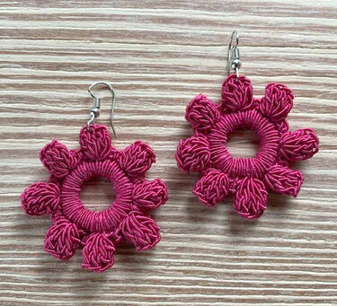 Gehäkelte Ohrringe mit ringförmigem Mittelteil und Noppenrand auf hellem Holzuntergrund