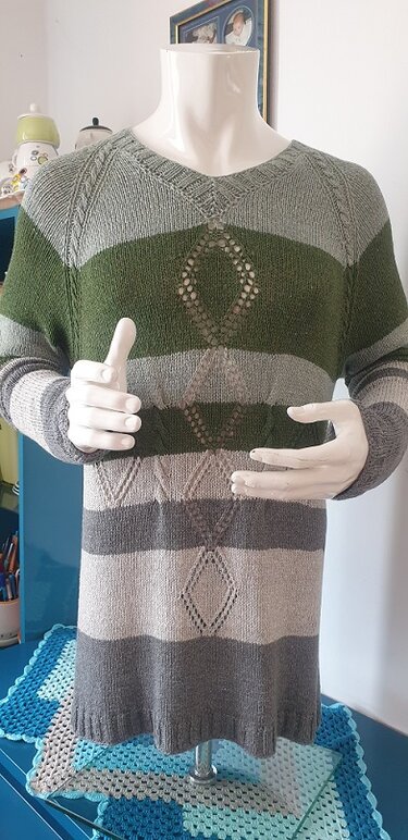 Gestrickter Herrenpullover mit V-Ausschnitt, breiten Oliv- und Graustreifen und Rauten-Lochmuster auf Schaufensterpuppe.
