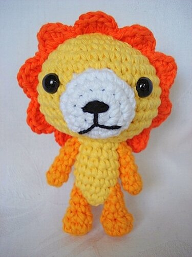 gelb-oranger gehäkelter Amigurumi-Löwe mit schwarzen Augen und weißer Schnauze