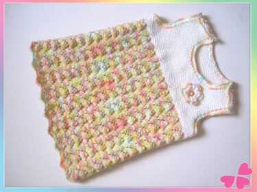 gestricktes ärmelloses Babykleid in Pastell mit weißer Brust und Blütenapplikation