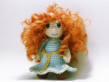 Gehäkelte Amigurumi-Puppe mit roten Locken und blauem Kleid